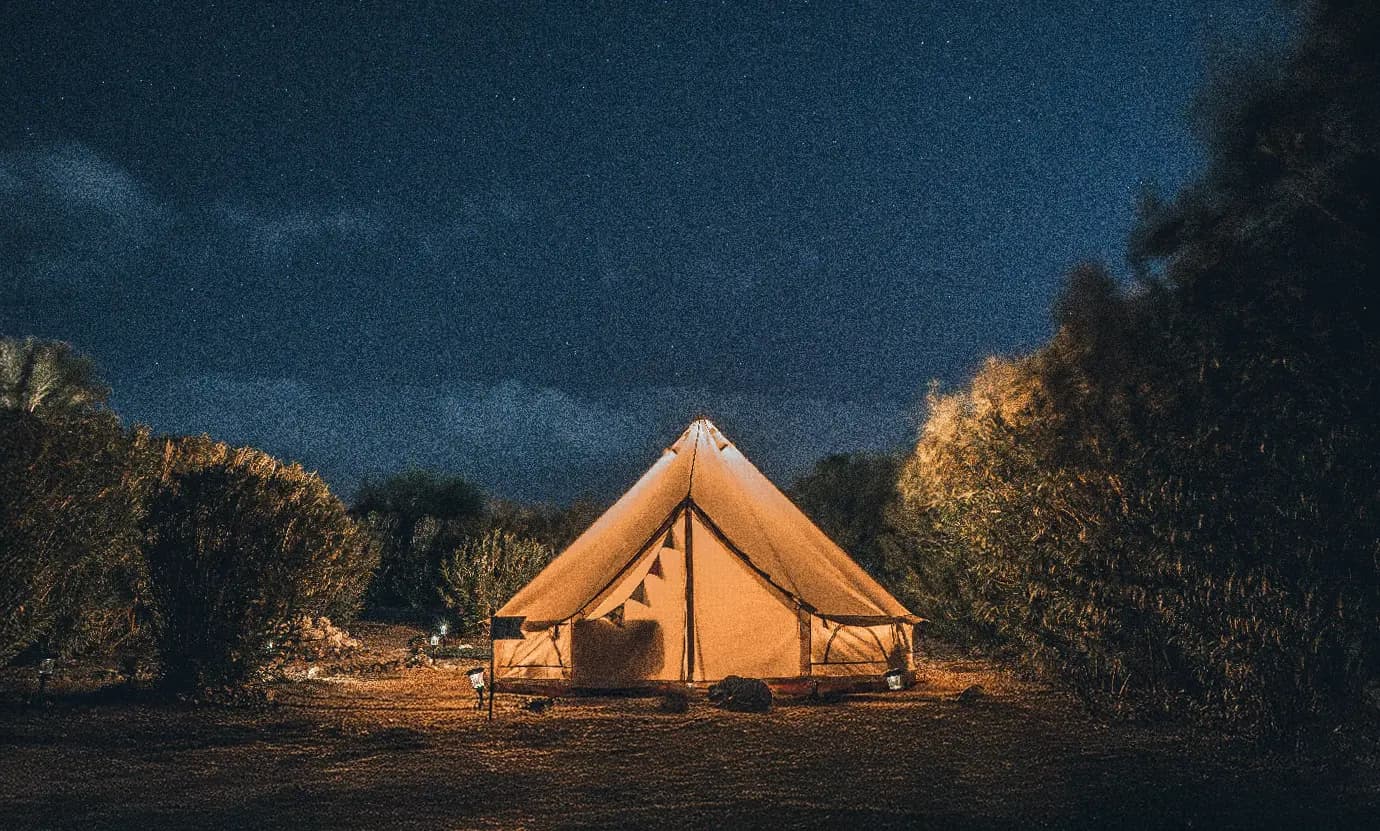 Glamping tent lit at night under a starry sky